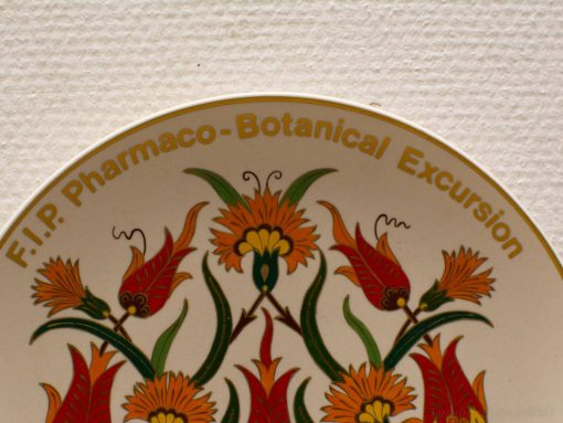 Botanical decorative plate from 1987, featuring vibrant flowers and F.I.P. Pharmaco-Botanical Excursion.