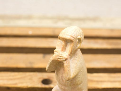 Wooden monkey sculpture symbolizing silence and reflection, showcasing exquisite craftsmanship and detail.