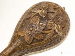 Elegant carved wooden decoration with floral motifs in a warm, rich tone.