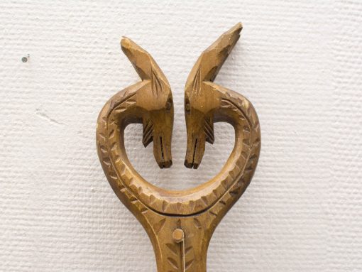Intricately carved wooden sculpture featuring two animal heads symbolizing connection and harmony.