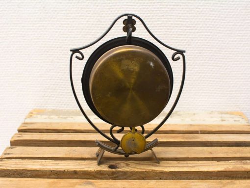 Elegant vintage brass bell on ornate wrought iron stand, perfect for enhancing any decor.
