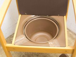 Vintage wooden toilet chair with bowl for comfort and accessibility in care settings.
