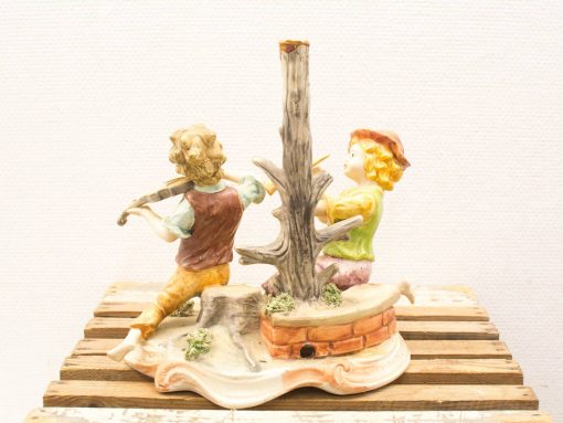 Charming porcelain figurine of playful children making music outdoors in vibrant colors.