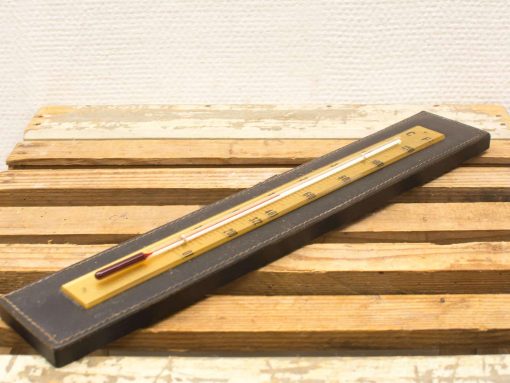 Antique leather-bound thermometer with ruby mercury bulb, showcasing classic craftsmanship and vintage charm.