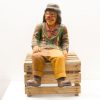 Whimsical wooden clown on crate: a charming vintage circus decoration for any space.