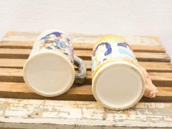 Vintage decorative beer steins with artistic handles on a rustic wooden surface.