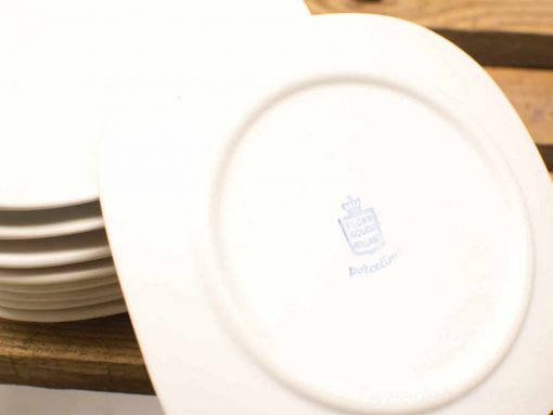 Elegant white ceramic plates with a crown logo, perfect for fine dining and special occasions.