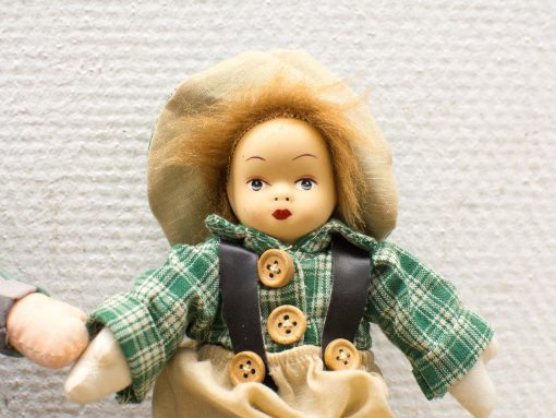 Charming vintage doll with straw hat and green checkered outfit, evoking nostalgia and whimsy.