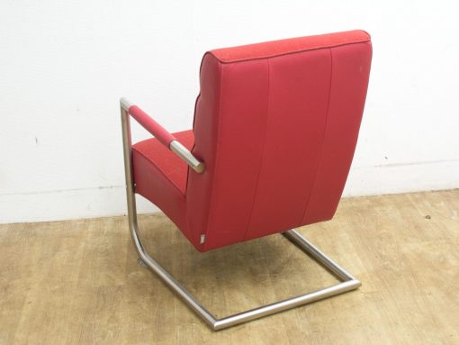 Vibrant red minimalist armchair with sleek metal frame for contemporary living spaces.