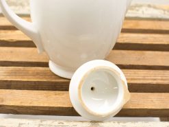 Elegant white porcelain teapot with a glossy finish on rustic wooden background.