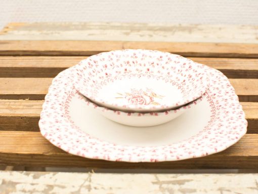Elegant rose-patterned porcelain bowls on a rustic wooden table, perfect for dining occasions.