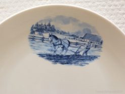 Delft blue plate featuring a serene farmer and horse in a rural landscape scene.