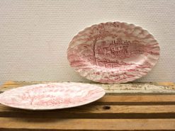 Elegant pink and white vintage ceramic platters with intricate pastoral designs for display or use.