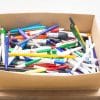Colorful array of pens and markers in a cardboard box for creative projects and writing.