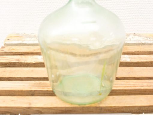 Elegant green glass bottle on rustic wood, perfect for home decor and collection.