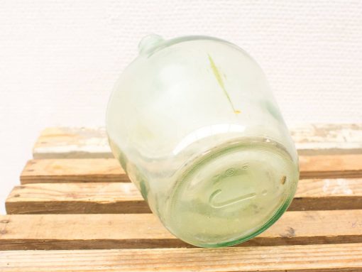 Vintage green glass jar with rustic wooden backdrop, perfect for decor and storage.