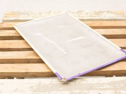 Vintage transparent sheet with metal frame on rustic wooden surface, evoking nostalgic charm.