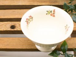 Vintage white ceramic bowl with floral design on rustic wood, adding elegance to home decor.