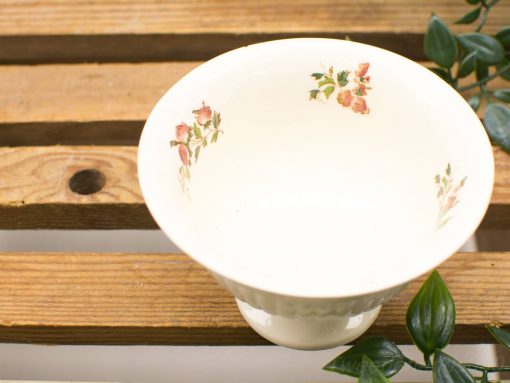 Vintage white ceramic bowl with floral design on rustic wood, adding elegance to home decor.
