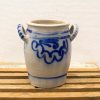 Handcrafted cream ceramic pot with blue swirl design and dual handles for rustic decor.