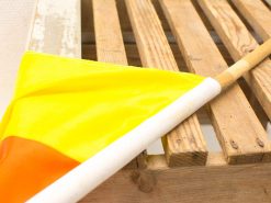 Vibrant yellow and orange flag on a rustic wooden surface, signaling attention and caution.