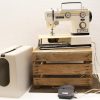 Vintage Diplomat sewing machine on rustic wooden pallet, featuring retro design and protective cover.
