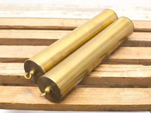 Vintage brass tubes with handles on rustic wood, showcasing craftsmanship and historical charm.