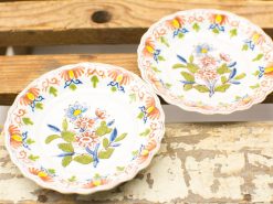 Elegant vintage ceramic plates featuring vibrant floral patterns on a rustic wooden surface.