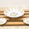 Charming vintage ceramic bowl set with floral designs on a rustic wooden table.