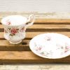 Elegant porcelain teacup and saucer set with pink rose design and gold accents.