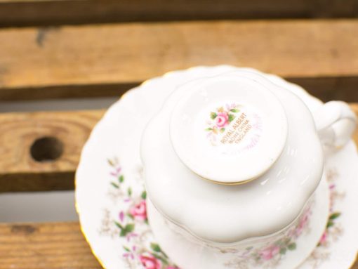 Elegant Royal Albert porcelain teacup and saucer with rose design and gold trim.