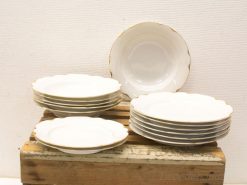 Elegant porcelain dishware set with scalloped edges and gold trim for formal dining occasions.