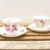 Elegant vintage floral teacups on a rustic wooden surface, perfect for afternoon tea.