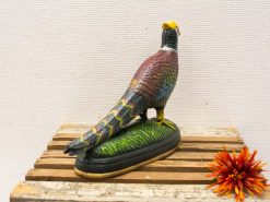 Handcrafted pheasant figurine with vibrant colors, paired with a decorative orange flower.