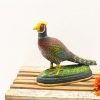 Vibrant pheasant figurine on grass base, accented with bright orange flower for decorative appeal.