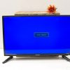 Sleek modern TV with wooden plank and vibrant artificial flower decor.