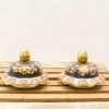 Elegant blue and gold decorative lids with floral patterns on a rustic wooden surface.