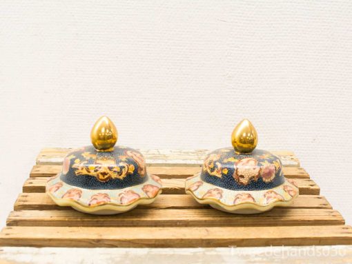 Elegant blue and gold decorative lids with floral patterns on a rustic wooden surface.