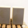 Sleek cream speakers on rustic wood, perfect for style and sound in any decor.