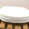 Elegant white oval plates stacked on rustic wooden surface for a stylish dining experience.