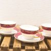 Elegant vintage tea cups and saucers with burgundy and gold accents on a rustic surface.