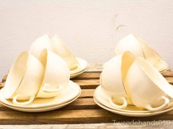 Charming vintage pale yellow teacups stacked on a rustic wooden crate for a nostalgic touch.