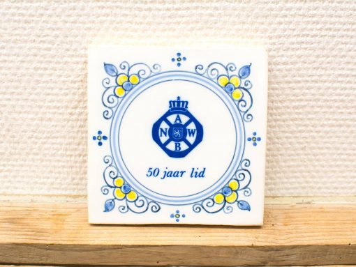 Ceramic tile celebrating 50 years of membership with ANWB, featuring floral designs and heraldic emblem.