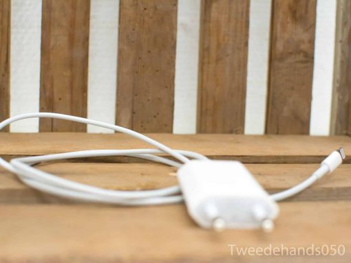 White charging cable on rustic wood, connecting to a compact charger for modern devices.