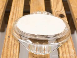 Elegant glass dish with glossy white interior on rustic wood surface, perfect for food presentation.