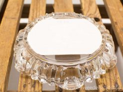 Elegant glass dish with label on rustic wooden surface for showcasing items.