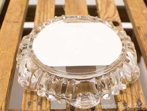 Elegant glass dish with label on rustic wooden surface for showcasing items.