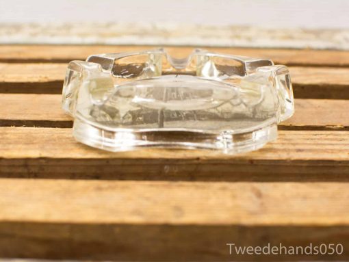 Elegant vintage glass ashtray on rustic wooden table for stylish décor and practical use.