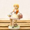 Charming porcelain figurine of a playful girl with braids, dressed in vintage style.