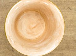 Elegant handmade ceramic bowl with a golden rim, featuring warm peach and off-white hues.